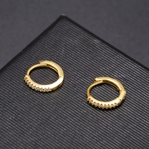 Macro detail of golden pavé hoop earrings with sparkling white zircons on a jewelry box