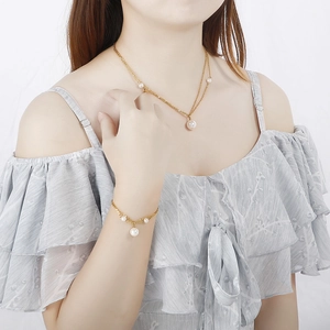 Elegant gold double-layered necklace and pearl bracelet jewelry set worn by a model