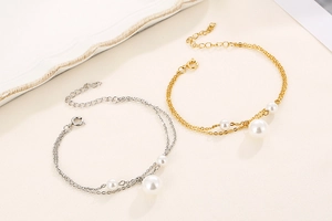 Detail view of double-layer gold and silver stainless steel bracelets with white pearls