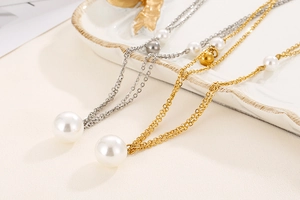 Detail view of double-layer stainless steel pearl necklaces in gold and silver on a tray
