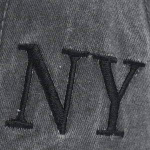 Macro view of 3D embroidered NY logo on washed charcoal grey cotton baseball cap
