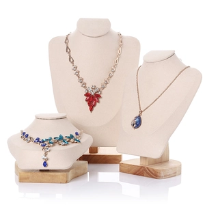 Three velvet necklace display stands with wooden bases in beige and grey for jewelry shops