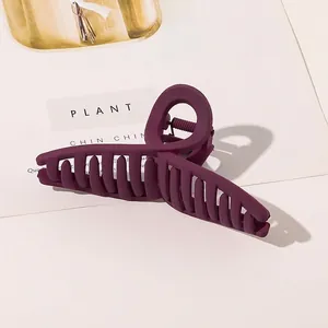 Close-up of large matte dark purple hair claw clip with interlocking teeth and metal spring