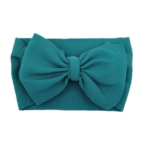 Macro shot of teal waffle knit fabric headband with a large decorative bow for infants