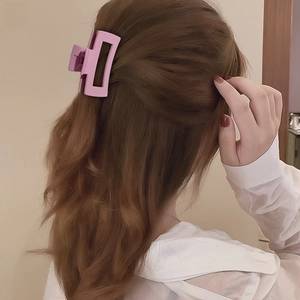 Detail of pink matte rectangular hair claw clip styling a low bun on a model back view