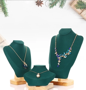 Three sizes of dark green velvet necklace busts with wooden bases for jewelry displays