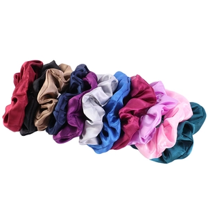 Set of eleven colorful satin silk scrunchies in various shades on a white background