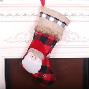 Classic red black plaid Christmas stocking with Santa Claus applique on white fireplace