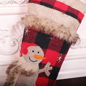Detailed close-up of a red buffalo plaid Christmas stocking with burlap snowman and faux fur