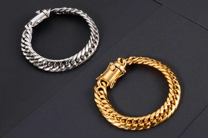 Détail de gros bracelets gourmette en or et argent avec fermoir carré sur fond sombre