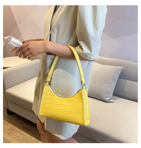 Detail showing the glossy yellow crocodile texture and metal buckle on the shoulder bag