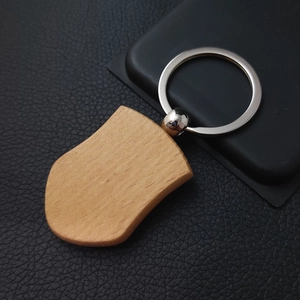 Close-up of a shield-shaped beech wood keychain with a silver metal ring on black leather