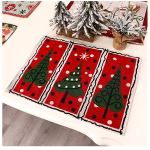Close-up of red linen Christmas placemat with green tree patterns and snowflake decor