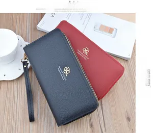 Detail of red and black lychee texture wallets with clover logo on wooden background