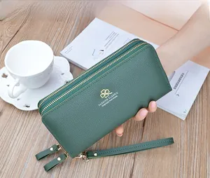Detail of dark green lychee pattern wallet with double zippers and golden clover logo