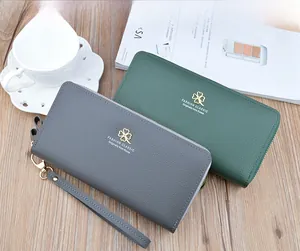 Detail of lychee textured leather long wallets with gold clover logo and wrist straps