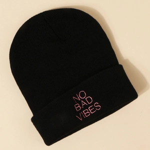 Détail de la broderie rose NO BAD VIBES sur un bonnet en maille côtelée noire