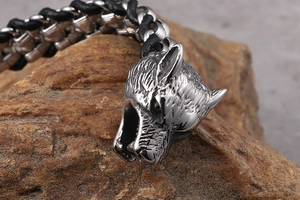 Macro shot of a wolf head buckle and braided leather bracelet on a rugged rock