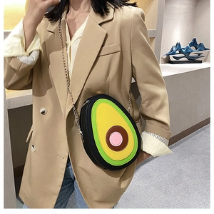 Creative avocado-shaped PU crossbody bag with metal chain shown on a beige blazer