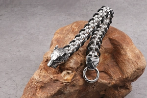 Detail of stainless steel wolf head buckle on black braided leather bracelet for men