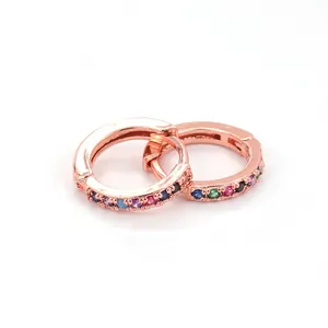 Macro shot of rose gold huggie hoop earrings with multi-colored rainbow cubic zirconia