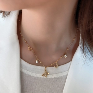 Close-up of golden butterfly necklace with pearl and rhinestones worn on neck