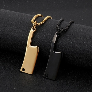 Close-up of mini cleaver pendants in gold and black on a textured display stand