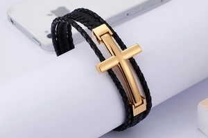Detail of multi-layer black braided leather bracelet with golden metallic cross clasp