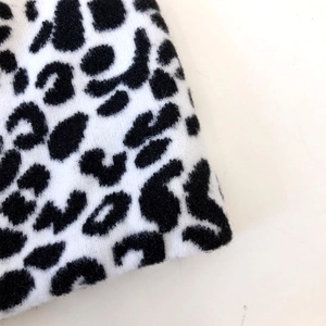 Detailed view of black and white leopard print knit fabric with soft plush texture