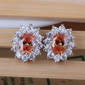 Macro view of sun-shaped earrings featuring orange zircon center and silver claw setting