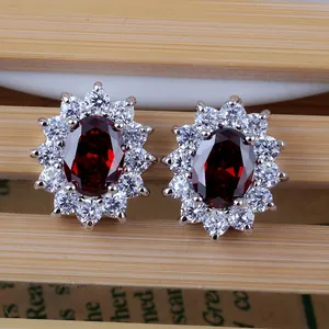 Classic silver stud earrings featuring oval red sapphire and halo cubic zirconia stones