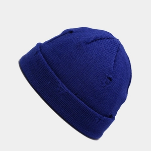 Close-up of distressed ripped details on dark blue knitted docker cap fabric