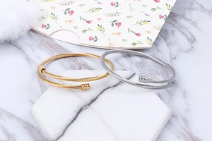 Detailed view of gold and silver spiral cable texture open bracelets on marble surface