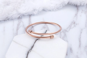 Detail of rose gold stainless steel wire bracelet with twisted design on marble tray