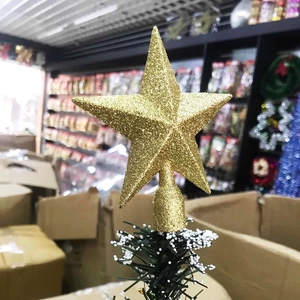 Detail of a 20cm gold glitter Christmas tree topper star on a snow-flocked branch