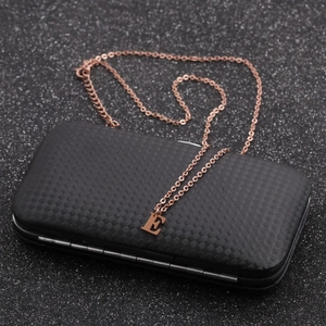 Macro detail of rose gold letter E pendant on an O-chain over a black textured surface