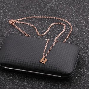 Close-up of rose gold H letter pendant on a textured black box with fine grid pattern