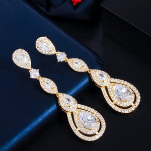 Macro detail of drop earrings with AAA zircons on a blue leather surface