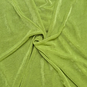 Macro shot of grass green knitted fabric texture with soft drapes and spiral fold detail