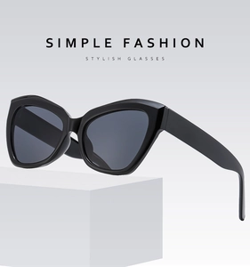 Detail of black cat-eye sunglasses with thick glossy frames on a white podium