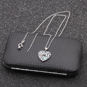 Silver MOM heart necklace with colorful zircons on a textured black jewelry box