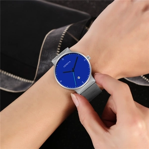 Minimalist men's quartz watch with deep blue dial and silver mesh band worn on wrist