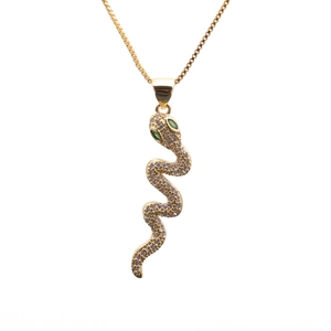 Detail of gold snake pendant necklace featuring clear zircons and green gemstone eyes