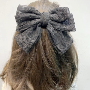 Detail of dark grey lace bow hair clip with intricate floral embroidery on the back of head