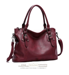 Close-up of wine red textured PU leather handbag with silver buckles and dual handles
