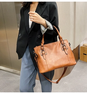 Brown leather tote bag featuring adjustable shoulder strap and metal buckle details