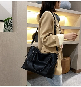Detail of black tote bag with lychee texture, silver studs and adjustable wide strap