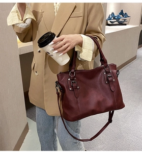 Close-up of wine red lychee pattern leather handbag with vintage metal buckle details