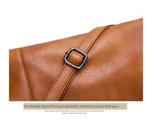 Detail of brown leather bag showing metal buckle, stitching, and adjustable strap