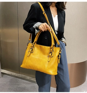 Close-up of mustard yellow tote bag with textured leather and retro buckle detail